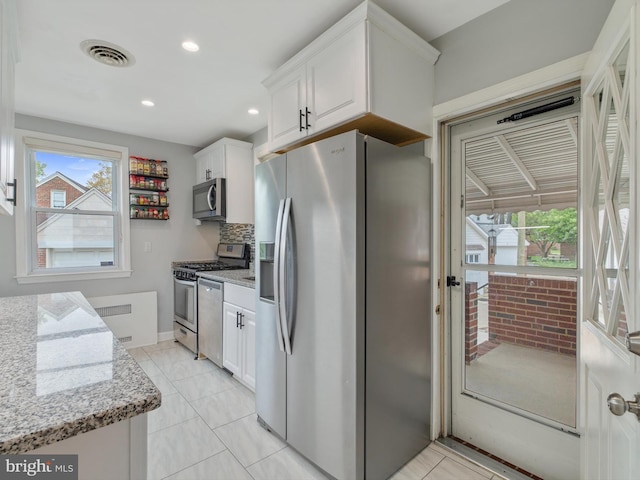 kitchen featuring stainless steel appliances, light tile patterned floors, visible vents, light stone counters, and white cabinets