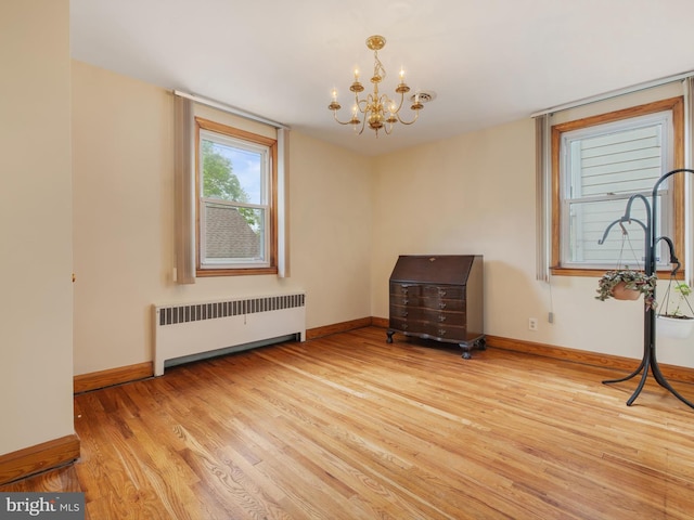 interior space featuring baseboards, radiator heating unit, wood finished floors, and an inviting chandelier