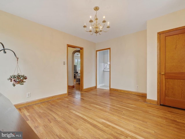 unfurnished dining area with an inviting chandelier, light wood finished floors, and baseboards