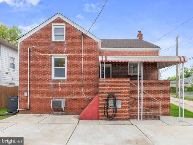 back of property featuring a chimney, cooling unit, a patio, and brick siding