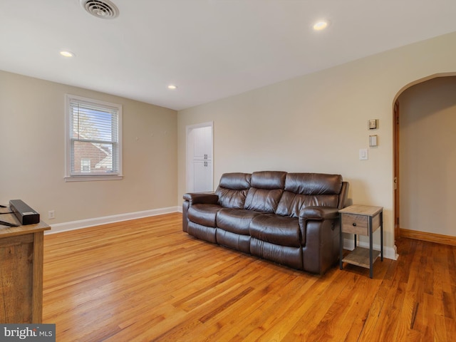 living room featuring recessed lighting, light wood-type flooring, visible vents, baseboards, and arched walkways