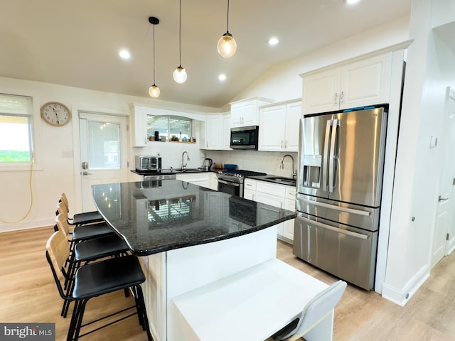 kitchen with a sink, appliances with stainless steel finishes, light wood-style flooring, and white cabinetry