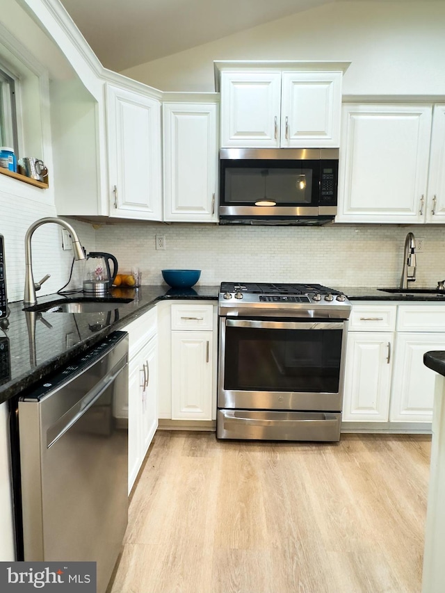 kitchen featuring a sink, light wood finished floors, appliances with stainless steel finishes, and lofted ceiling