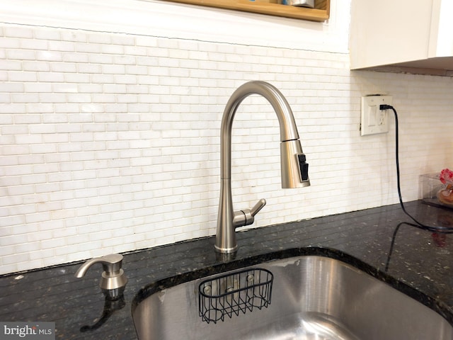 details with a sink, dark stone counters, and decorative backsplash