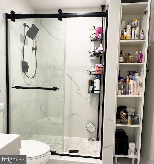 bathroom featuring a marble finish shower and toilet