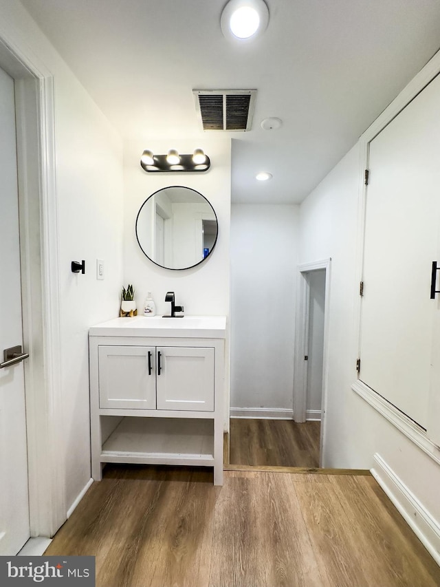 bathroom with baseboards, visible vents, wood finished floors, and vanity