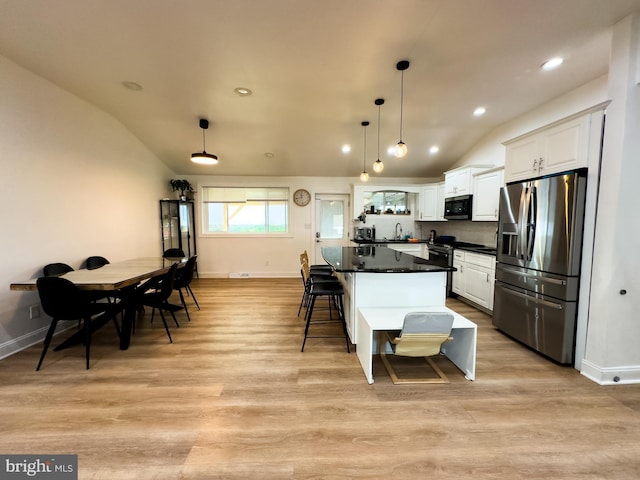 kitchen featuring lofted ceiling, dark countertops, a breakfast bar, baseboards, and stainless steel appliances