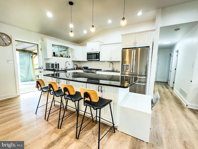 kitchen featuring a kitchen island, visible vents, light wood-style flooring, stainless steel appliances, and white cabinetry