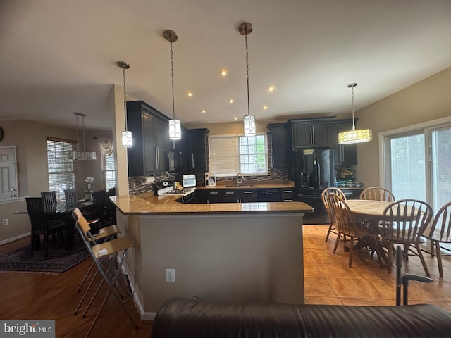 8800 Fenimore Pl, Bristow, VA 20136 - kitchen featuring black fridge with ice dispenser, stove, a sink, a peninsula, and tasteful backsplash