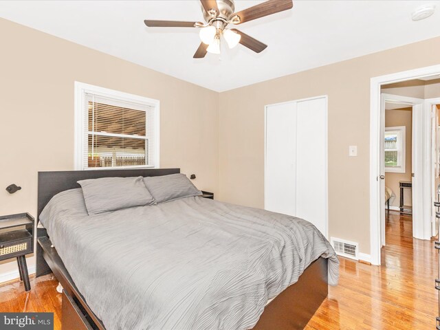bedroom featuring visible vents, a closet, baseboards, ceiling fan, and light wood finished floors