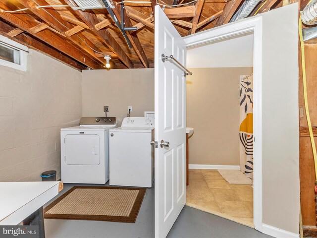 laundry room with laundry area, washing machine and dryer, and concrete block wall