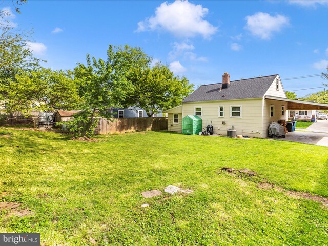 view of yard with central AC and fence