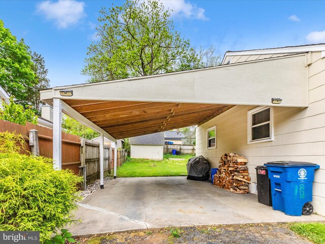 view of parking featuring fence, a carport, and a storage shed