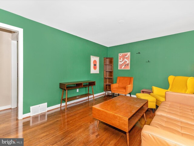 living room featuring visible vents, baseboards, and wood finished floors