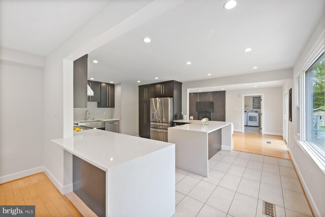 kitchen featuring a sink, light countertops, stainless steel appliances, and a peninsula