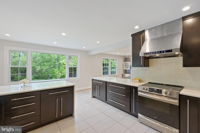 kitchen featuring decorative backsplash, stainless steel range with electric stovetop, light countertops, recessed lighting, and wall chimney exhaust hood