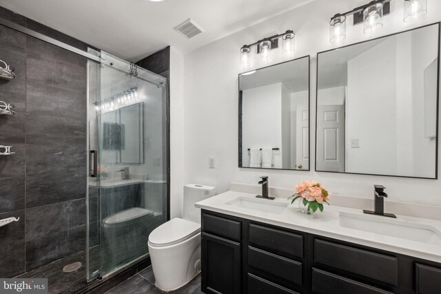 bathroom with a sink, a shower stall, toilet, and visible vents
