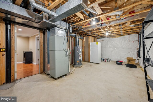 unfinished below grade area with water heater, heating unit, and freestanding refrigerator