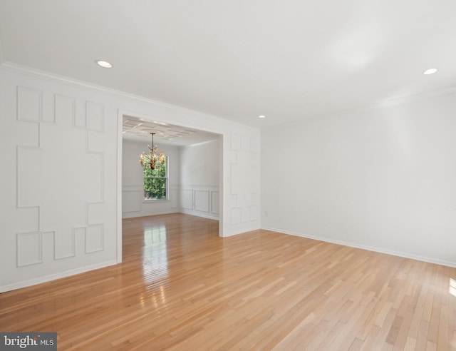 unfurnished room featuring crown molding, a decorative wall, recessed lighting, light wood-type flooring, and a chandelier