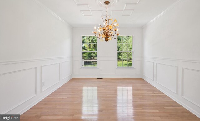 unfurnished dining area with a notable chandelier, wainscoting, light wood finished floors, and a decorative wall