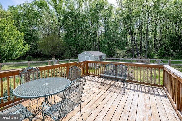 deck with a storage unit, a fenced backyard, outdoor dining space, and an outbuilding