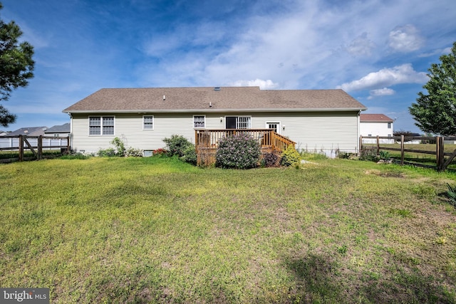 back of property featuring a wooden deck, a yard, and fence