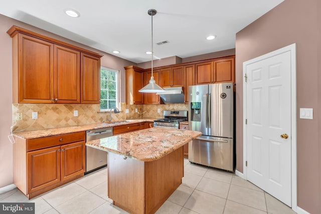 kitchen featuring light stone countertops, stainless steel appliances, brown cabinetry, and visible vents