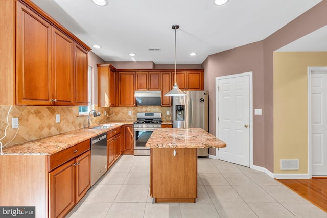 kitchen with visible vents, light stone countertops, a center island, a sink, and appliances with stainless steel finishes