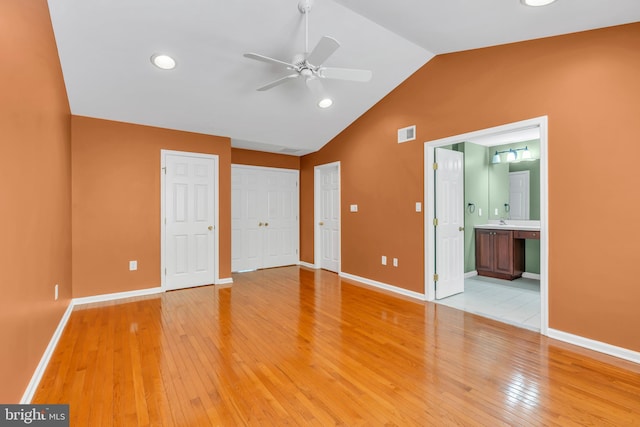 unfurnished bedroom with baseboards, visible vents, lofted ceiling, and light wood-style floors