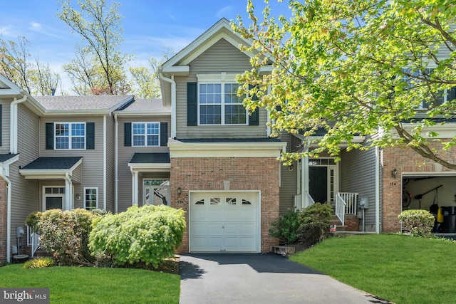 view of front of house featuring brick siding, driveway, a front yard, and a garage