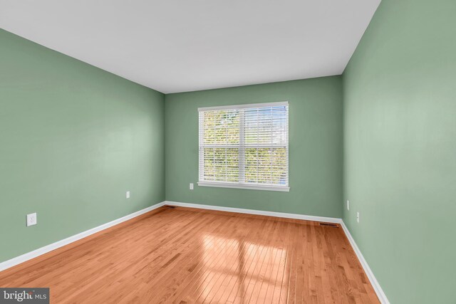 unfurnished room with baseboards and wood-type flooring