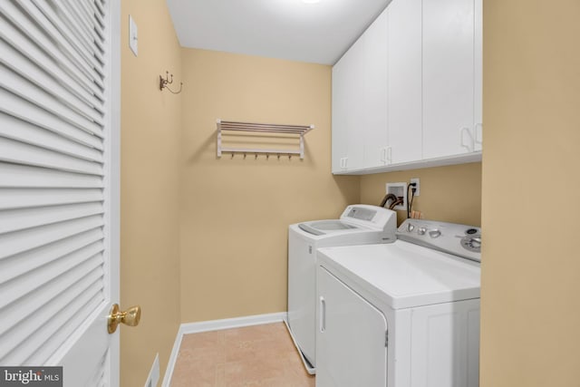 washroom with washer and dryer, baseboards, light tile patterned floors, and cabinet space