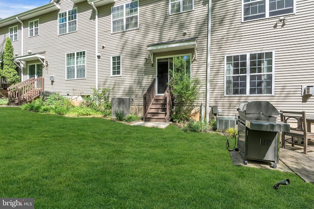 rear view of property featuring central AC unit, a yard, and entry steps