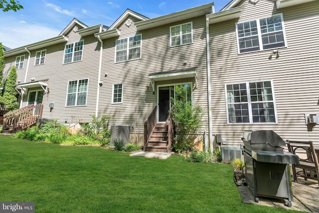 rear view of property with a lawn, central air condition unit, and entry steps