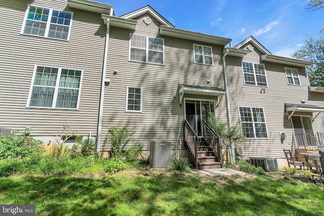 view of front of home with entry steps, central AC, and a front lawn