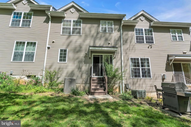 rear view of house with a lawn, central AC unit, and entry steps