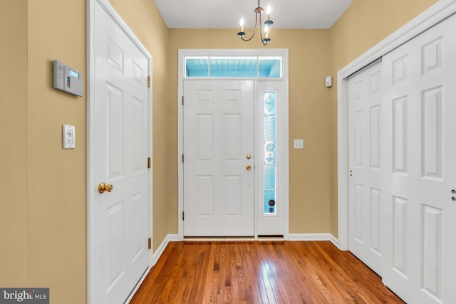 foyer entrance with baseboards, a chandelier, and wood finished floors