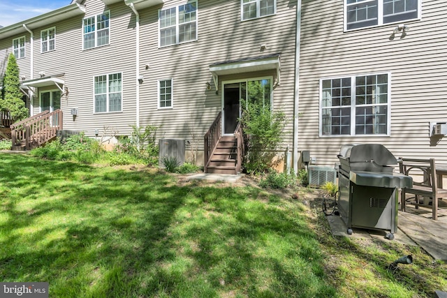 back of house featuring entry steps, central air condition unit, and a yard