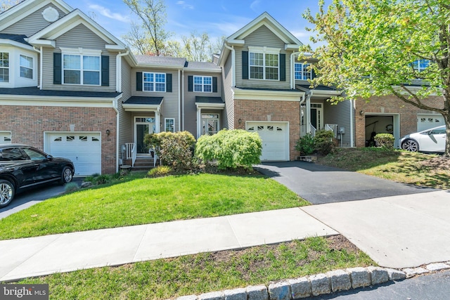 multi unit property with brick siding, a garage, a front lawn, and driveway