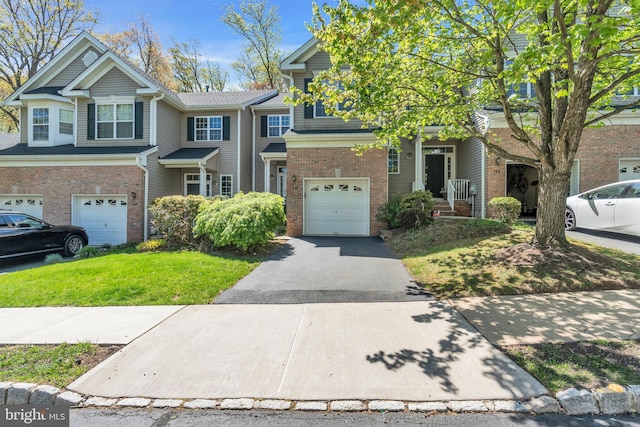 multi unit property with an attached garage, a front yard, driveway, and brick siding
