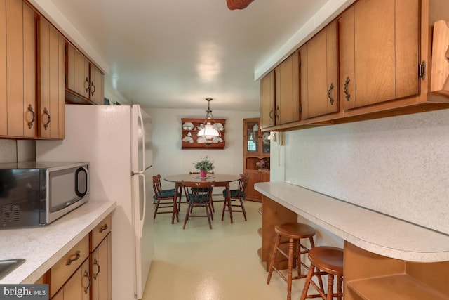 kitchen with light countertops, stainless steel microwave, and brown cabinets