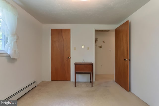 unfurnished room with visible vents, light carpet, and baseboard heating