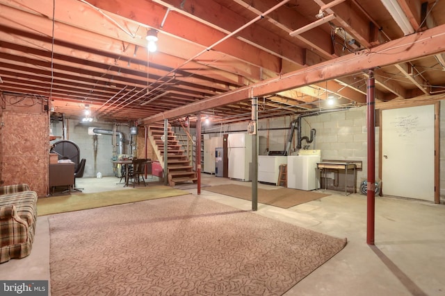 unfinished basement featuring freestanding refrigerator, stairs, and washing machine and clothes dryer