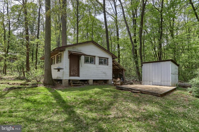 back of property featuring a lawn and an outbuilding