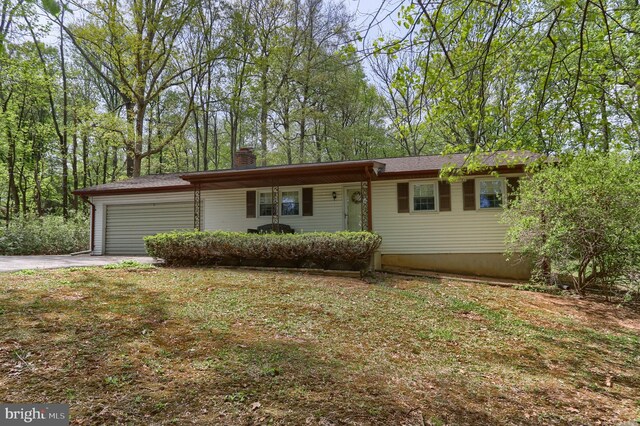 ranch-style house with covered porch, an attached garage, a chimney, and driveway