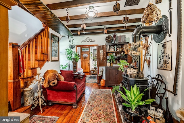 living area featuring visible vents, beam ceiling, and hardwood / wood-style flooring