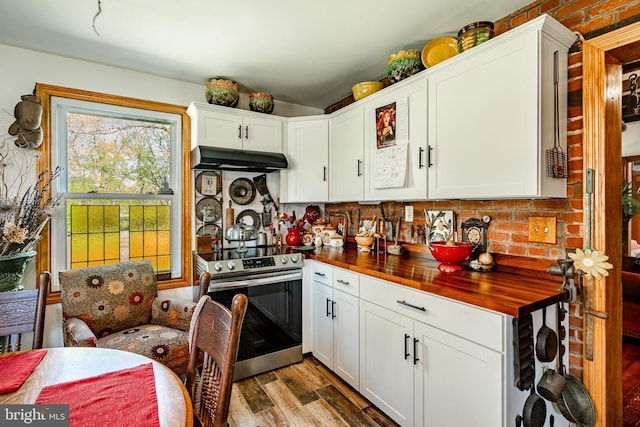 kitchen with white cabinets, wood counters, under cabinet range hood, stainless steel electric stove, and wood finished floors