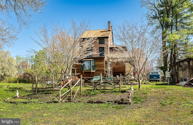 back of house featuring a chimney and a yard