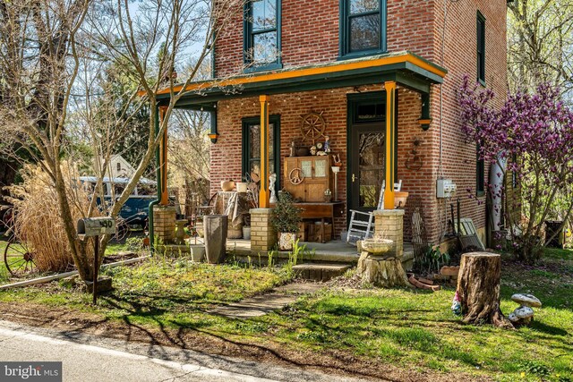 entrance to property with covered porch and brick siding