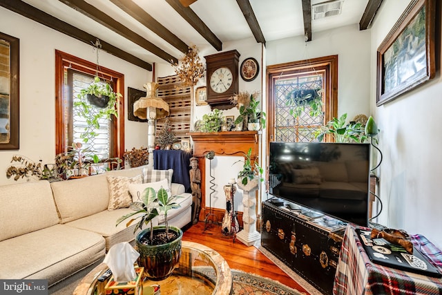 living area with a wealth of natural light, wood finished floors, visible vents, and beamed ceiling